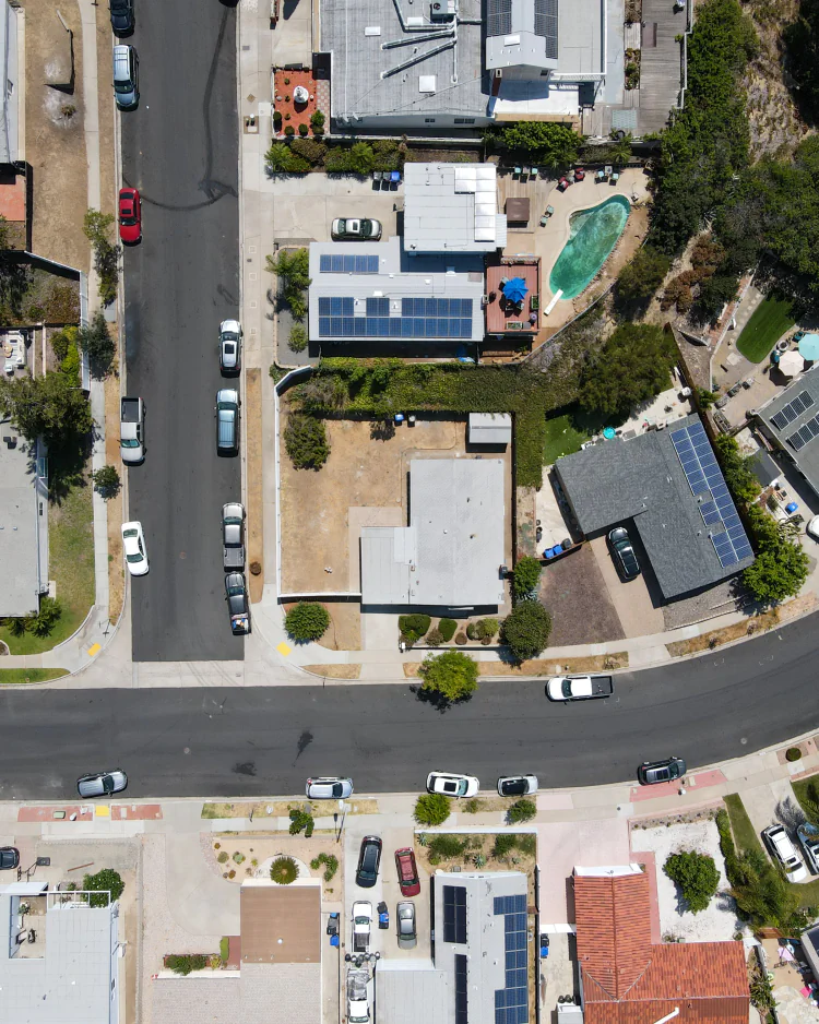 Aerial view of a San Diego residential block with streets, roofs, yards, parking, and solar panels