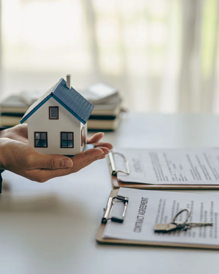 Model home, documents, and house keys on a desk