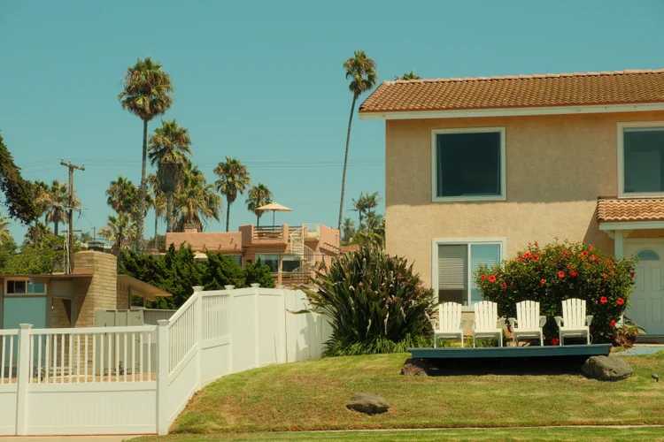 Two-story San Diego home with a tile roof, front lawn, and palm trees.