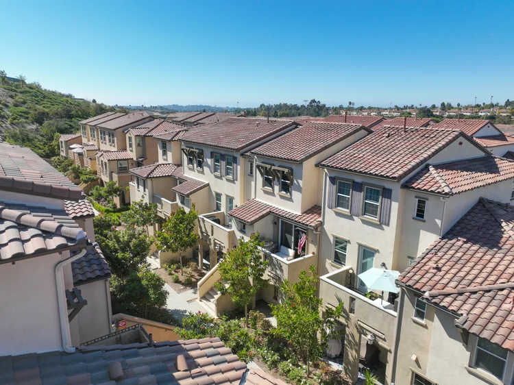 Attached residential buildings with tile roofs and landscaped shared walkways.