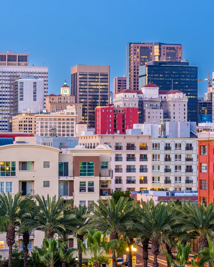 Little Italy condo buildings and the downtown San Diego skyline above a palm-lined street
